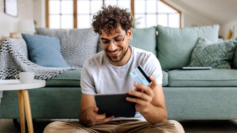 Man holding credit card and tablet.