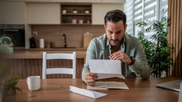 Man reads mail at kitchen table.