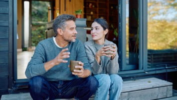 Couple sitting and talking outside of house.