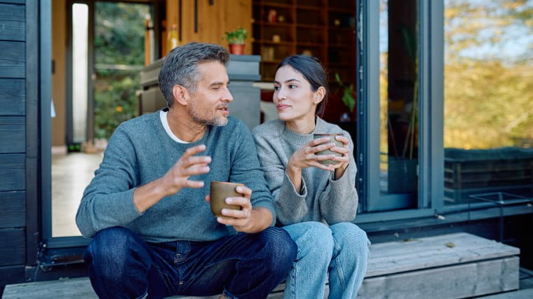Couple sitting and talking outside of house.