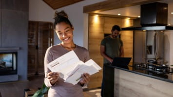 Excited young woman opening letter.