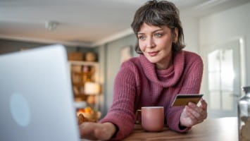 Woman holding credit card while using laptop.