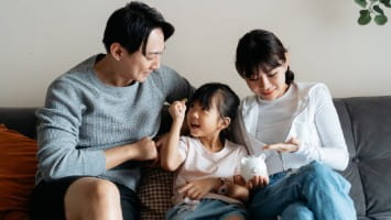 Couple with young daughter and piggy bank.