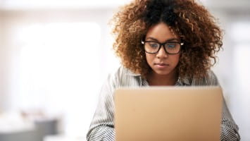 Young woman researching information on laptop.