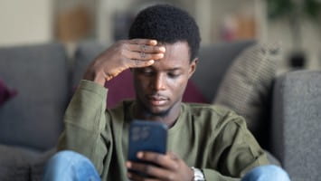 Worried young man looks at phone.