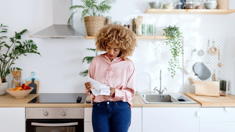 Woman reading a receipt in her kitchen.