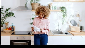 Woman reading a receipt in her kitchen.