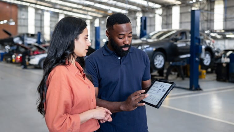 Man showing woman information on a tablet.