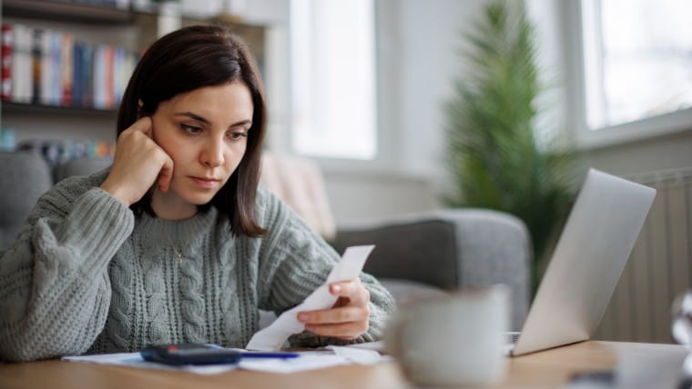 Worried young woman looking at bills.