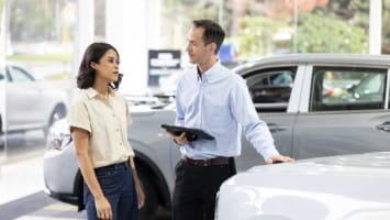 Woman talking to salesman at car dealership.