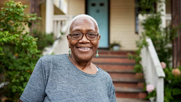 Elderly woman in front of house.