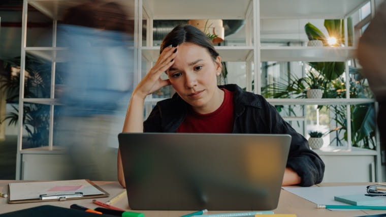 Stressed out young woman looking at laptop.