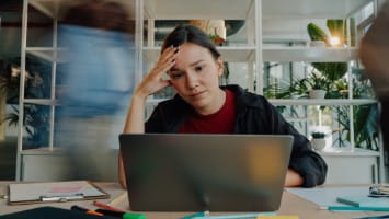 Stressed out young woman looking at laptop.