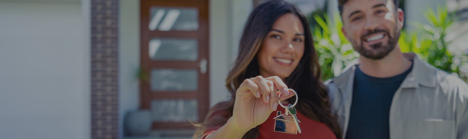 Woman and man proudly show off the keys to their new home.