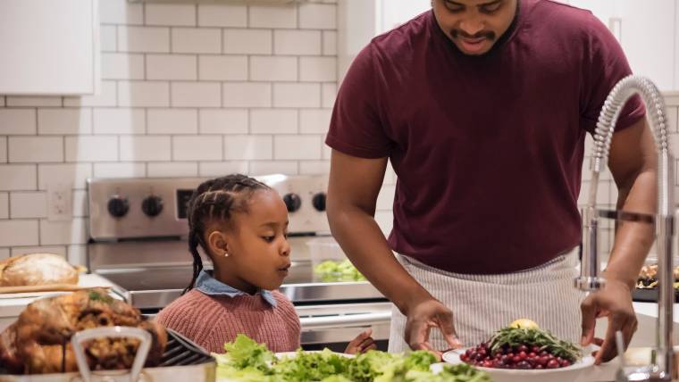 father and young daughter prepping Thanksgiving dinner together