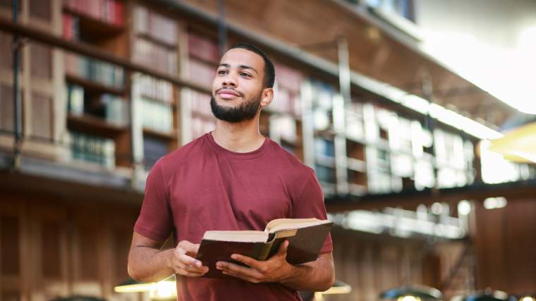 man holding a book in a library