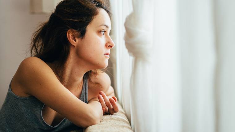 woman looking out the window sadly