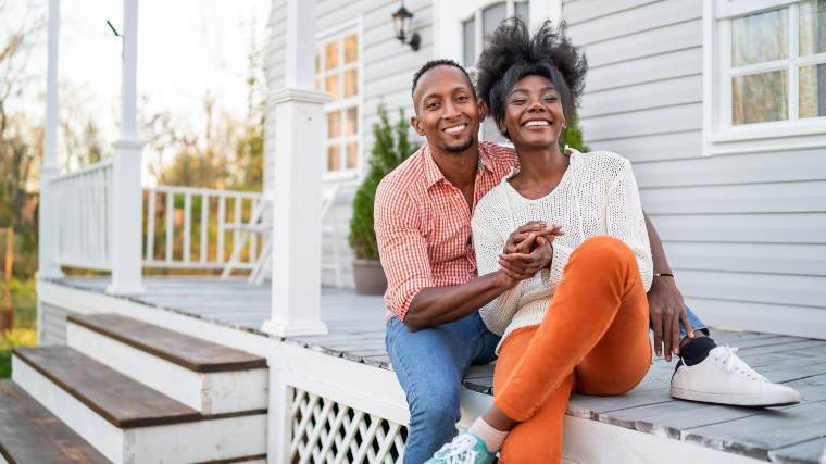 Young couple sitting on the porch of their first house.