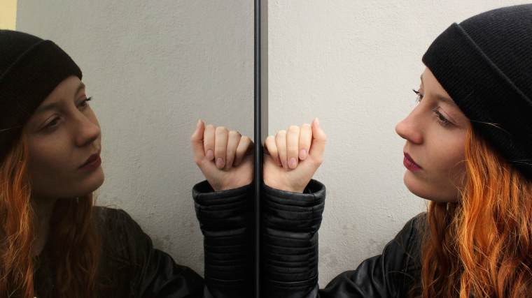 Young woman looking at herself in the mirror