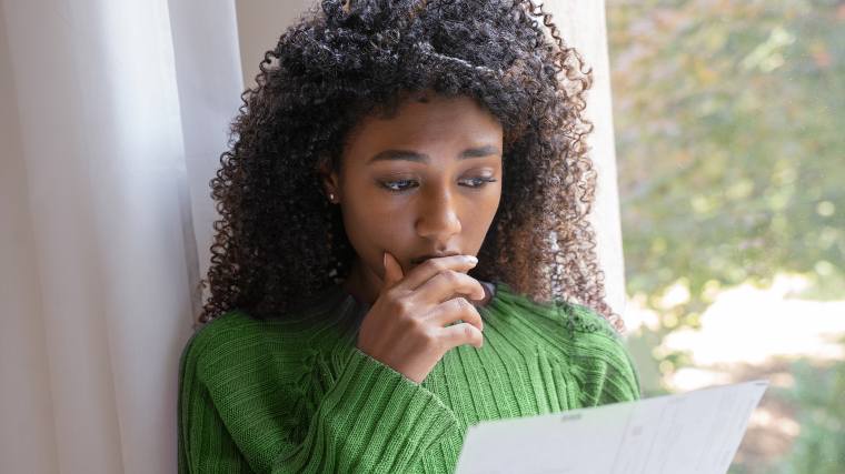 Concerned woman reading a credit card rejection letter.