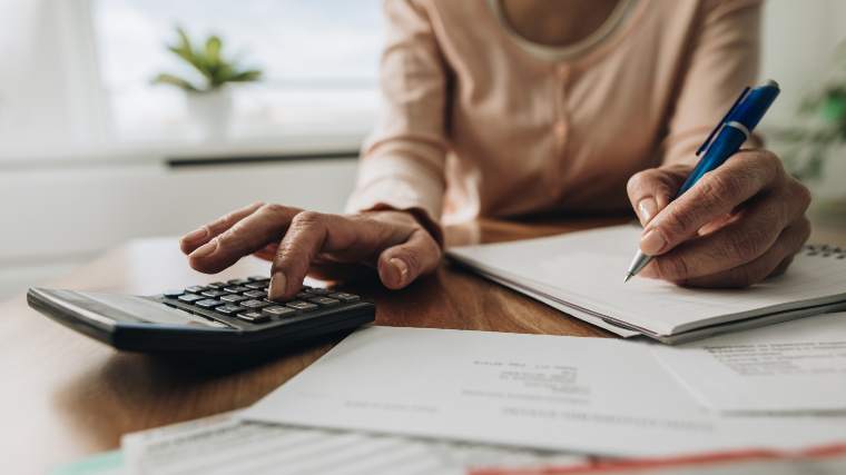 Woman doing calculations with a pen and calculator.