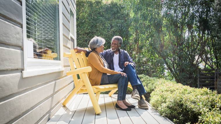 An elderly couple sitting on the porch together