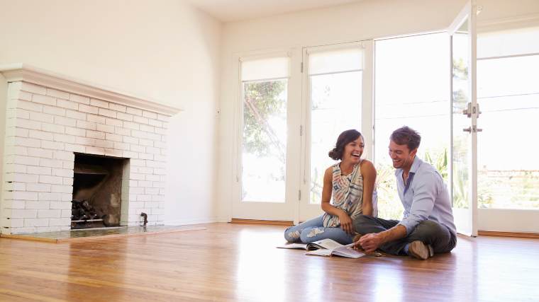 Young couple sitting together in their new home, which has no furniture.