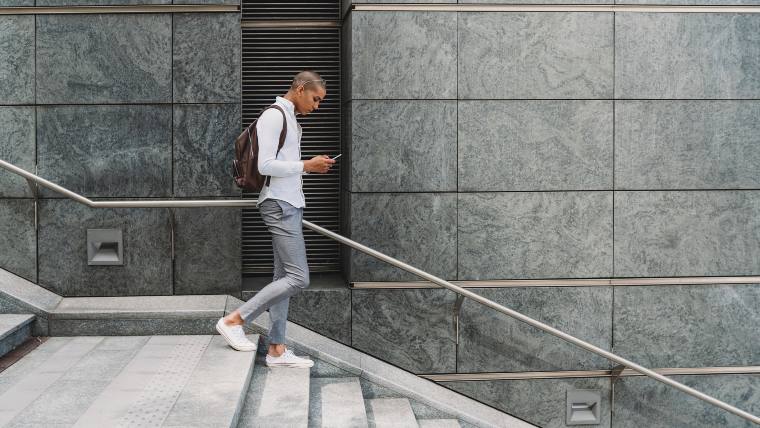 Young man walking and reading something on his cellphone.