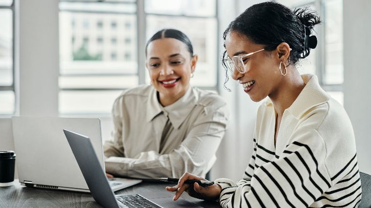 Two women reviewing info on a laptop.