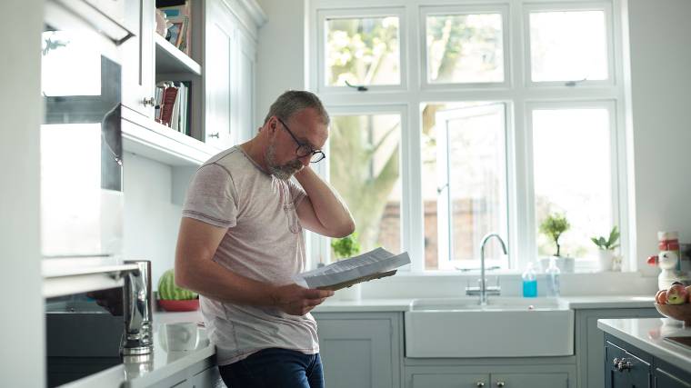 Man reading letter in his kitchen.