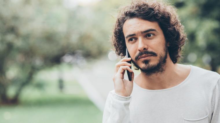 Worried man talking on his phone in the park.