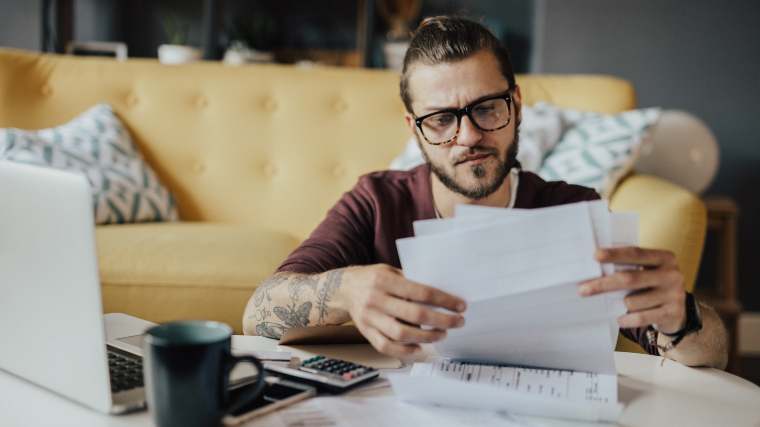 Man sitting in front of pile of bills, trying to understand his options.