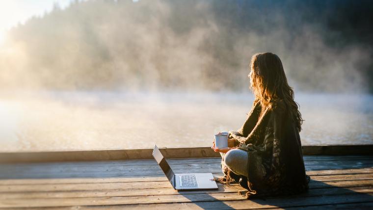 Woman using laptop while sitting outside.