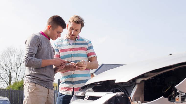 Two men exchanging insurance information after a car accident.