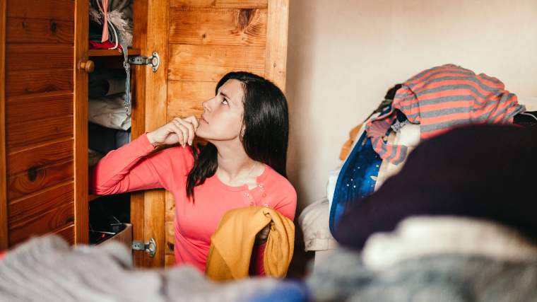 Young woman trying to clean out her closet.