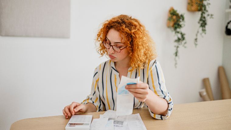 Woman working on budget at kitchen table.