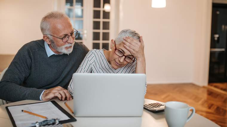 concerned senior couple reviewing information on their laptop
