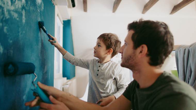 father and son painting wall together