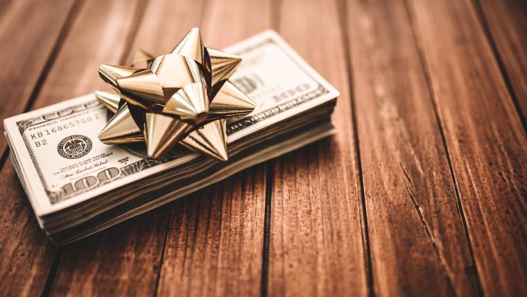 stack of dollar bills with holiday bow on top