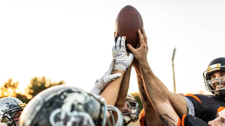 football players holding up a football together