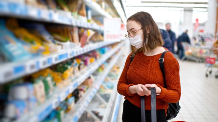 young woman shopping for groceries with a mask on