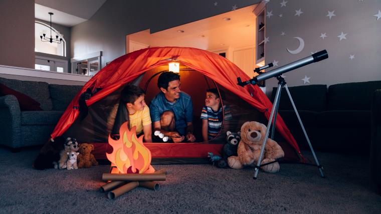 Father camping indoors with his young kids