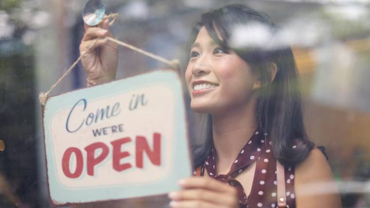 Woman putting out an open sign on her business