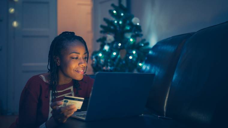 woman making an online purchase in front of Christmas tree