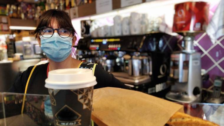 barista wearing a mask and cashing out customer