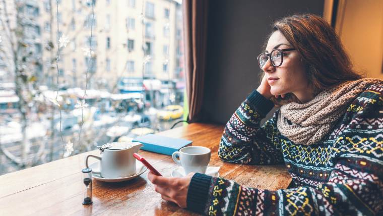 woman reviewing information on her phone at a coffee shop