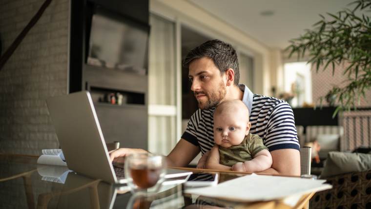 father reviewing banking statements with small child on his lap