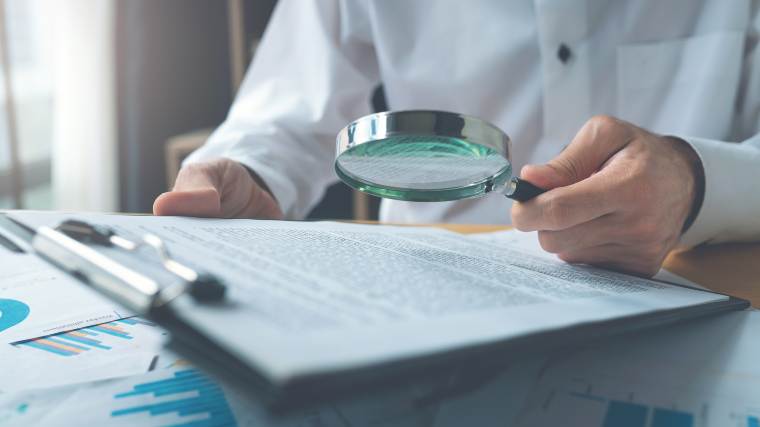 man reading document with magnifying glass