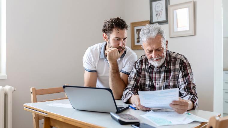 Man helping elderly father fill out paperwork.