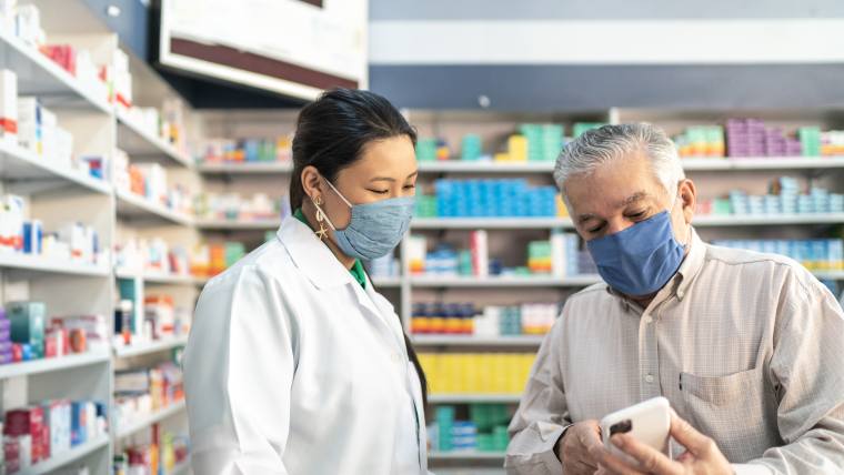 senior aged customer speaking with pharmacist